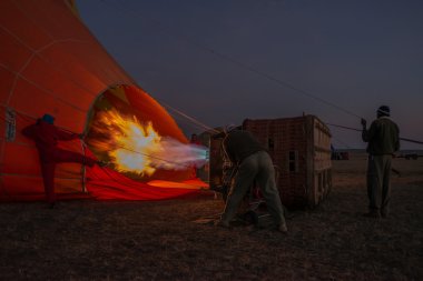 Men before dawn inflating hot air balloon