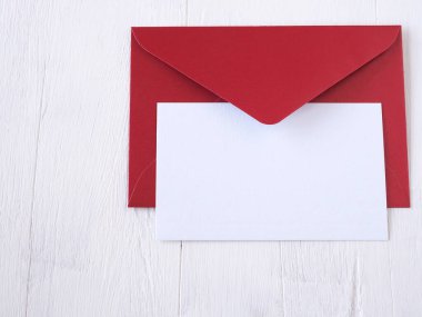 Ahşap masanın üzerinde kırmızı zarfın üzerindeki yazı için yeri olan beyaz kart kağıdı.