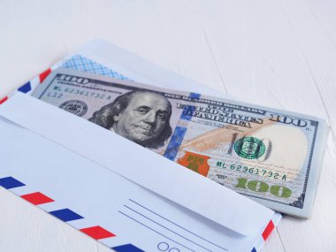Beyaz bir masanın üzerinde zarfın içinde 100 dolarlık banknot. 100 numarada seçici odak