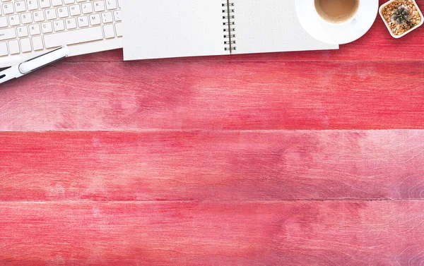 Flat lay office red wooden desktop with blank notebook and keyboard, pen, coffee, cactus. Top view with space for text. Business and education concept