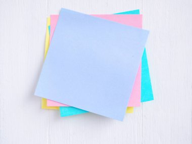 Yapışkan not (post-it) beyaz bir ahşap üzerine yığılmış. Mesajınız için boş alan ve şablon