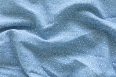 Üst görüntü, açık mavi kumaşın yakın çekim görüntüsü, ince, eşit dağılmış beyaz benekli deseni var. Görüntü materyalin dokusuna ve tekrarlanan nokta motifine odaklanır