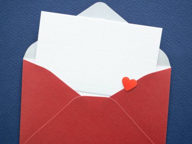 Açık kırmızı zarf, beyaz kart ve mavi dokuda küçük kalp. Sevgililer Günü için romantik aşk mektubu konsepti. Davetiye tasarımı için metin kopyalama alanı ile birlikte.