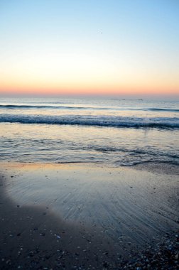 Güzel yaz manzarası, kumsalda gün batımı, parlak kum ve dalgalar, güzel renkler..