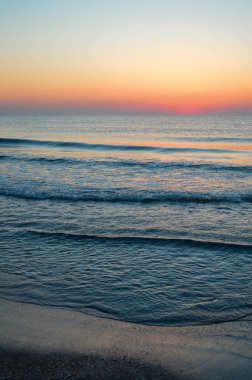 Güzel yaz manzarası, kumsalda gün batımı, parlak kum ve dalgalar, güzel renkler..