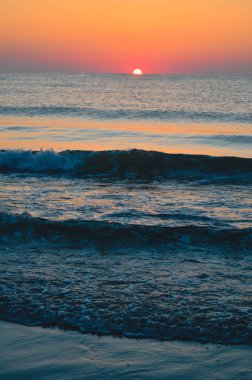 Güzel yaz manzarası, kumsalda gün batımı, parlak kum ve dalgalar, güzel renkler..