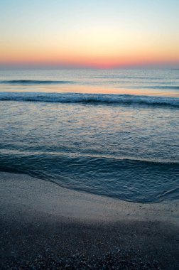 Güzel yaz manzarası, kumsalda gün batımı, parlak kum ve dalgalar, güzel renkler..