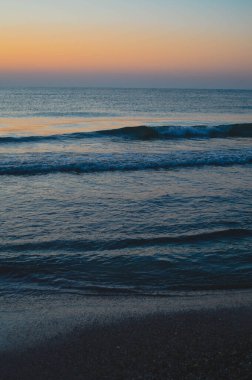 Güzel yaz manzarası, kumsalda gün batımı, parlak kum ve dalgalar, güzel renkler..