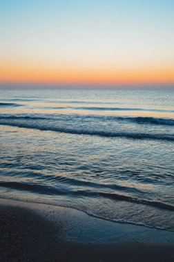 Güzel yaz manzarası, kumsalda gün batımı, parlak kum ve dalgalar, güzel renkler..