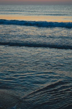 Güzel yaz manzarası, kumsalda gün batımı, parlak kum ve dalgalar, güzel renkler..