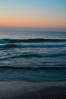 Güzel yaz manzarası, kumsalda gün batımı, parlak kum ve dalgalar, güzel renkler..