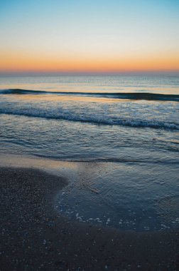 Güzel yaz manzarası, kumsalda gün batımı, parlak kum ve dalgalar, güzel renkler..