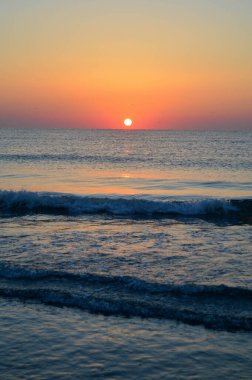 Güzel yaz manzarası, kumsalda gün batımı, parlak kum ve dalgalar, güzel renkler..