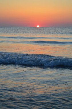 Güzel yaz manzarası, kumsalda gün batımı, parlak kum ve dalgalar, güzel renkler..