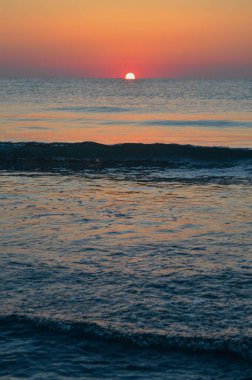 Güzel yaz manzarası, kumsalda gün batımı, parlak kum ve dalgalar, güzel renkler..