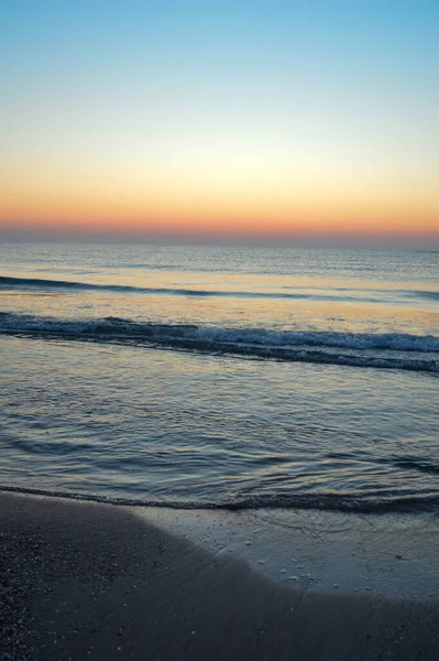 Güzel yaz manzarası, kumsalda gün batımı, parlak kum ve dalgalar, güzel renkler..