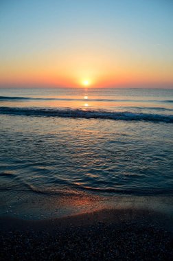 Güzel yaz manzarası, kumsalda gün batımı, parlak kum ve dalgalar, güzel renkler..