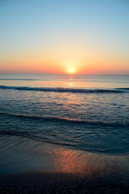 Güzel yaz manzarası, kumsalda gün batımı, parlak kum ve dalgalar, güzel renkler..