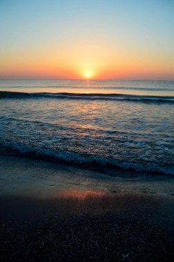 Güzel yaz manzarası, kumsalda gün batımı, parlak kum ve dalgalar, güzel renkler..