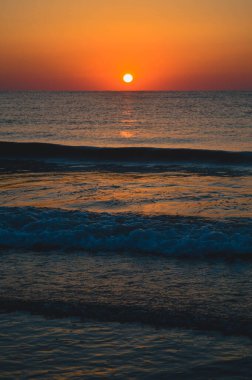 Güzel yaz manzarası, kumsalda gün batımı, parlak kum ve dalgalar, güzel renkler..