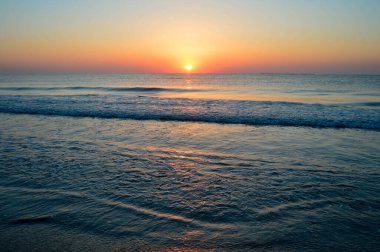 Güzel yaz manzarası, kumsalda gün batımı, parlak kum ve dalgalar, güzel renkler..