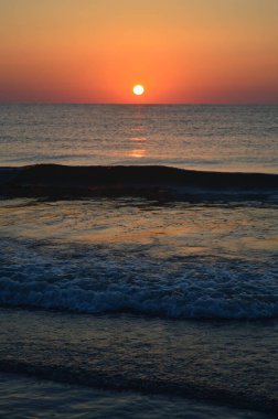 Güzel yaz manzarası, kumsalda gün batımı, parlak kum ve dalgalar, güzel renkler..