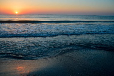 Güzel yaz manzarası, kumsalda gün batımı, parlak kum ve dalgalar, güzel renkler..