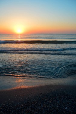 Güzel yaz manzarası, kumsalda gün batımı, parlak kum ve dalgalar, güzel renkler..