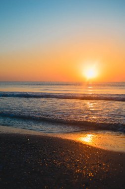 Güzel yaz manzarası, kumsalda gün batımı, parlak kum ve dalgalar, güzel renkler..