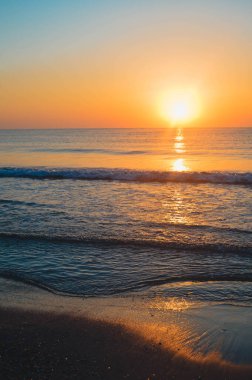 Güzel yaz manzarası, kumsalda gün batımı, parlak kum ve dalgalar, güzel renkler..