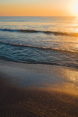 Güzel yaz manzarası, kumsalda gün batımı, parlak kum ve dalgalar, güzel renkler..