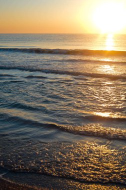 Güzel yaz manzarası, kumsalda gün batımı, parlak kum ve dalgalar, güzel renkler..