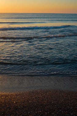 Güzel yaz manzarası, kumsalda gün batımı, parlak kum ve dalgalar, güzel renkler..