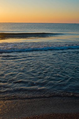 Güzel yaz manzarası, kumsalda gün batımı, parlak kum ve dalgalar, güzel renkler..
