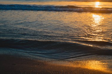 Güzel yaz manzarası, kumsalda gün batımı, parlak kum ve dalgalar, güzel renkler..
