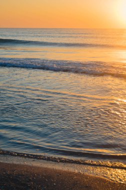 Güzel yaz manzarası, kumsalda gün batımı, parlak kum ve dalgalar, güzel renkler..