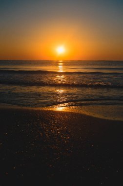 Güzel yaz manzarası, kumsalda gün batımı, parlak kum ve dalgalar, güzel renkler..