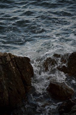 Deniz dalgaları kayalara çarpıyor. Deniz dalgaları kayalara çarpıyor. Denizde fırtına, karanlık, karamsar fotoğraf.