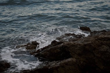 Deniz dalgaları kayalara çarpıyor. Deniz dalgaları kayalara çarpıyor. Denizde fırtına, karanlık, karamsar fotoğraf.