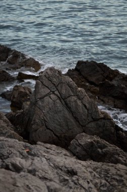 Deniz dalgaları kayalara çarpıyor. Deniz dalgaları kayalara çarpıyor. Denizde fırtına, karanlık, karamsar fotoğraf.