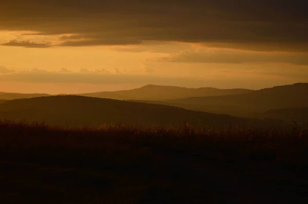 Sunset in nature, orange light, sky with clouds, field and woods, landscape