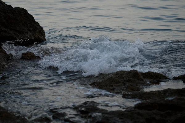 Sea waves crashing into rocks. Storm at the sea, dark, moody photo. Clear water, sharp rocks. Close up wave.
