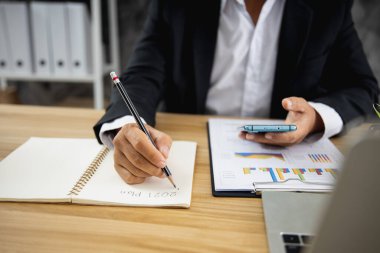 İş adamı 2021 'de karar vermek ve kağıt üzerinde iş planlamak için telefona bakıyor.