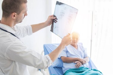 Doktor, röntgen filmlerine bakın ve yaşlı hastalara hastalıklarını anlatın.  