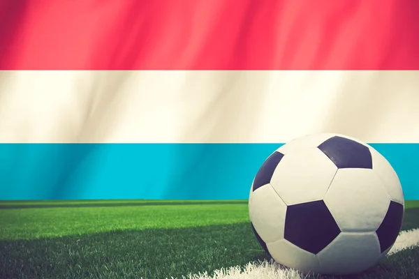 Balón de fútbol y bandera nacional de Luxemburgo se encuentra en el gr verde —  Fotos de Stock