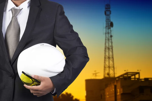Ingeniero sosteniendo casco blanco para la seguridad de los trabajadores en segundo plano — Foto de Stock