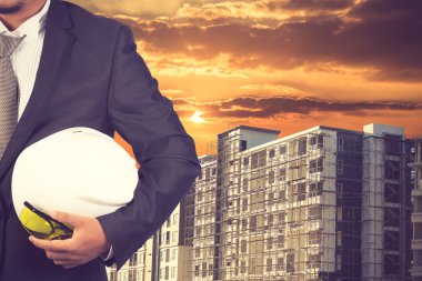 const binanın zemine, çalışmak için kask tutan mühendisi