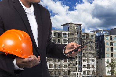 const binanın zemine, çalışmak için kask tutan mühendisi