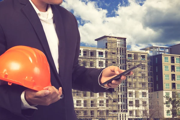 const binanın zemine, çalışmak için kask tutan mühendisi