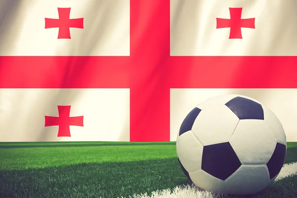 Fußball und georgische Nationalflagge liegen auf dem grünen Rasen — Stockfoto
